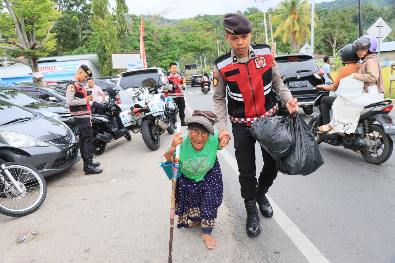 Personel Sat Samapta Bantu Warga Menyeberang di Depan Pospam Dermaga Singkarak